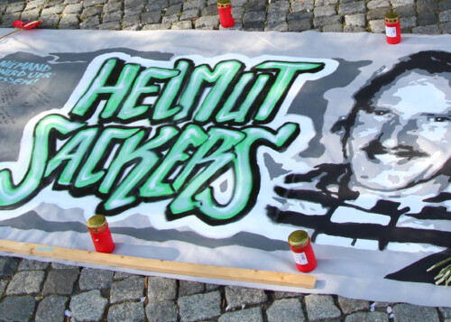 Transparent mit dem Bild von Helmut Sacker. Kerzen und Blumen.